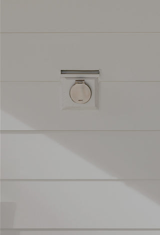 A brushed stainless steel house hydrant v1+ installed on a home with white lap siding and a mounting block.