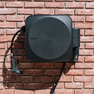 Aquor Retractable Hose Reel in Charcoal with Utility Spray Nozzle mounted on brick