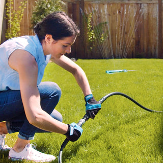 A woman connects the hose adapter to turn on a sprinkler.