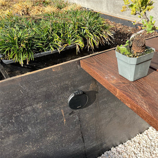 A customer photo of an installed matte black house hydrant v1+ installed on the side of a planter.