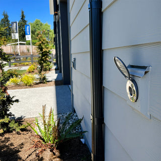 A customer photo of an installed slate gray house hydrant v1+ installed on light blue lap siding.