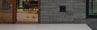 A matte black house hydrant v1+ installed on brick with a black mounting box.