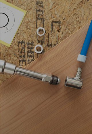 A photo of the Aquor house hydrant, half inch PEX expansion elbow inlet, and PEX line, demonstrating where the inlet spins off.