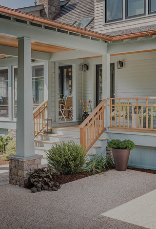 A light blue home with a front deck.