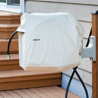 An cream colored retractable Hose Reel with a hose reel cover installed on a wooden deck next to a house wall.