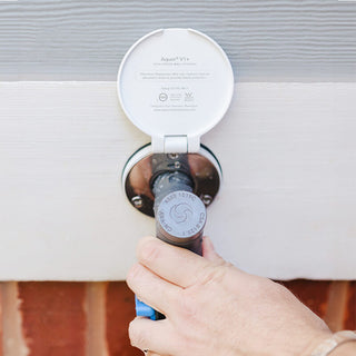 A hand connecting a comfort grip vb hose connector to a house hydrant v1+ with a matte white v1+ debris cover.
