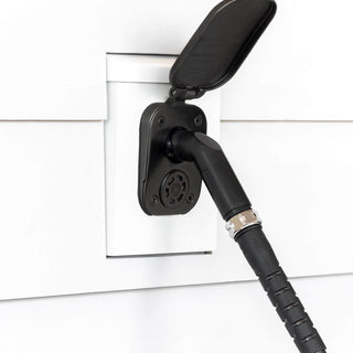 A jet black angled hose connector connected to a matte black house hydrant v2+ installed on white lap siding with a mounting block.