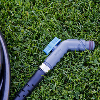 Slate gray removable faucet hose connector and hose laying in the grass.