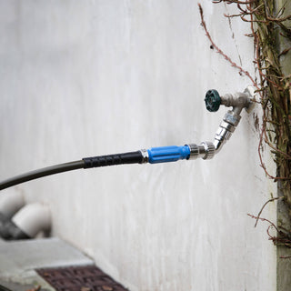 A hose and straight hose connector inserted into a faucet adapter which is attached to a hose bib installed on a stucco wall.