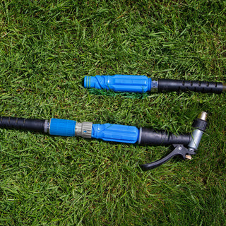 A blue hose adapter sits connected in the grass.