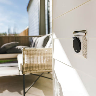 A matte black v1+ debris cvoer shown on white lap siding. 