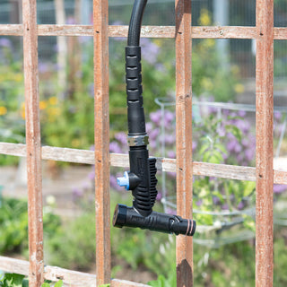 A jet black vacuum breaker hose connector and hose dangling over a fence.