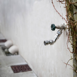 A faucet adapter attached to a hose bib installed on a stucco wall.