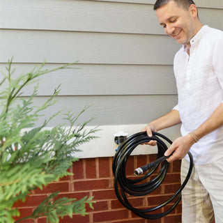 A man holding a jet black garden hose.