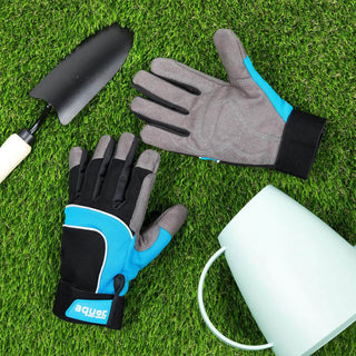 The Aquor utility gloves lay in green turf grass next to a watering can and trowel.