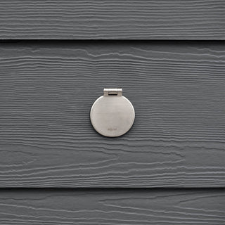 The brushed stainless house hydrant v1+ with a closed cover on dark gray lap siding.