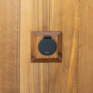 A matte black v1+ debris cover shown on wooden siding with a wooden mounting block.