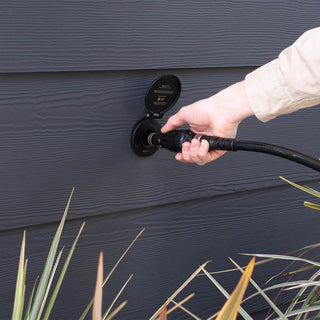A man inserting the wide grip vb hose connector and hose into the matte black house hydrant V1+.