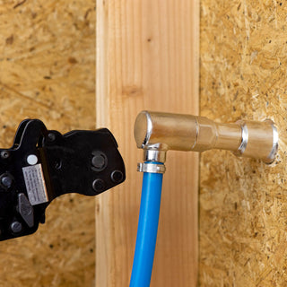 A PEX crimp tool crimping the ring fittings to connect the PEX line to the half inch elbow PEX crimp inlet.