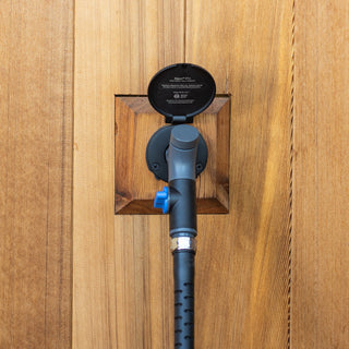 A comfort grip vb hose connector and hose plugged into a matte black house hydrant v1+ installed on wooden siding and wooden mounting block.