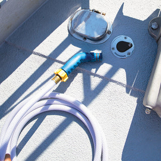 A marine deckwash installed into the floor of a boat, an angled hose connector and hose sits next to it. 