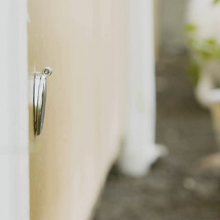 A person connecting to a brushed stainless house hydrant v1+ with a slate gray removable faucet hose connector. 