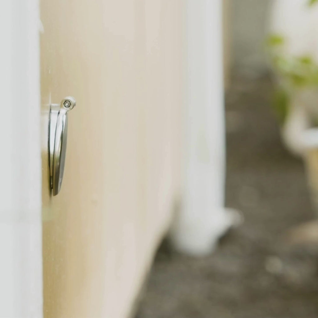 A person connecting to a brushed stainless house hydrant v1+ with a slate gray removable faucet hose connector. 