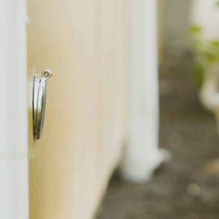 A person connecting a slate gray wide grip vb hose connector to a brushed stainless house hydrant v1+.