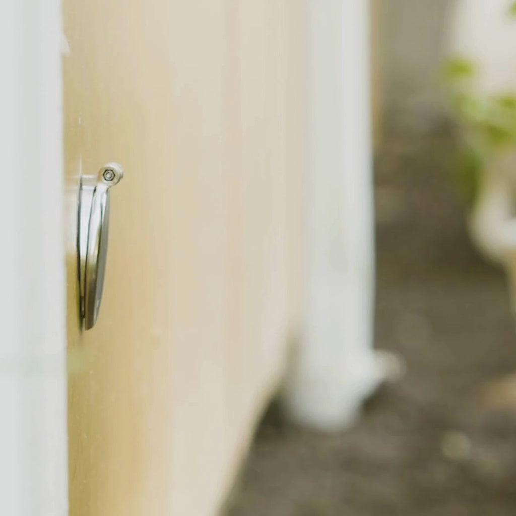 A person connecting a slate gray wide grip vb hose connector to a brushed stainless house hydrant v1+.