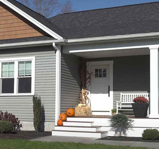 A home with pumpkins on the stairs leading to the front door.
